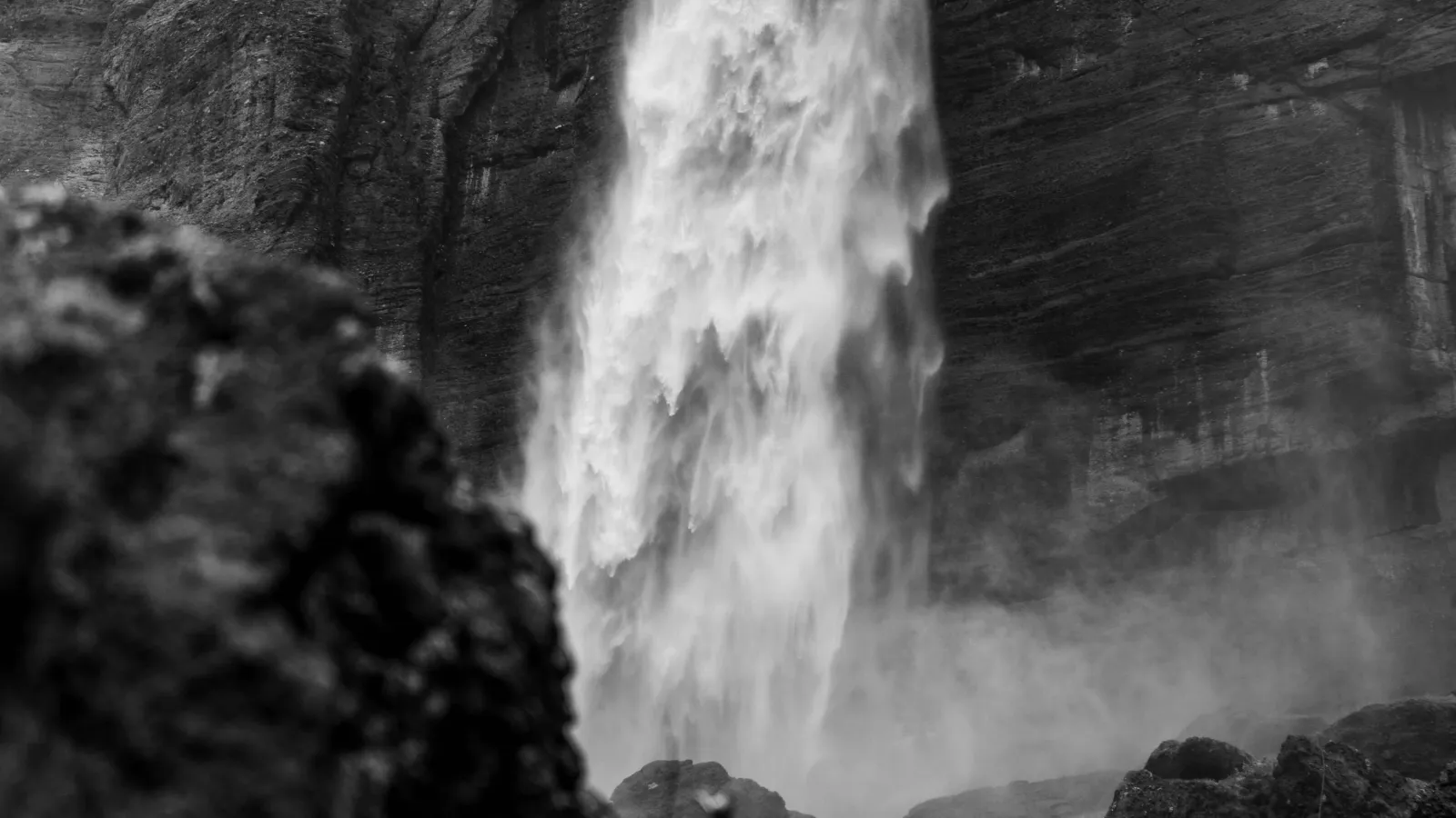 Black-and-white close-up of a waterfall crashing between steep rock walls.
