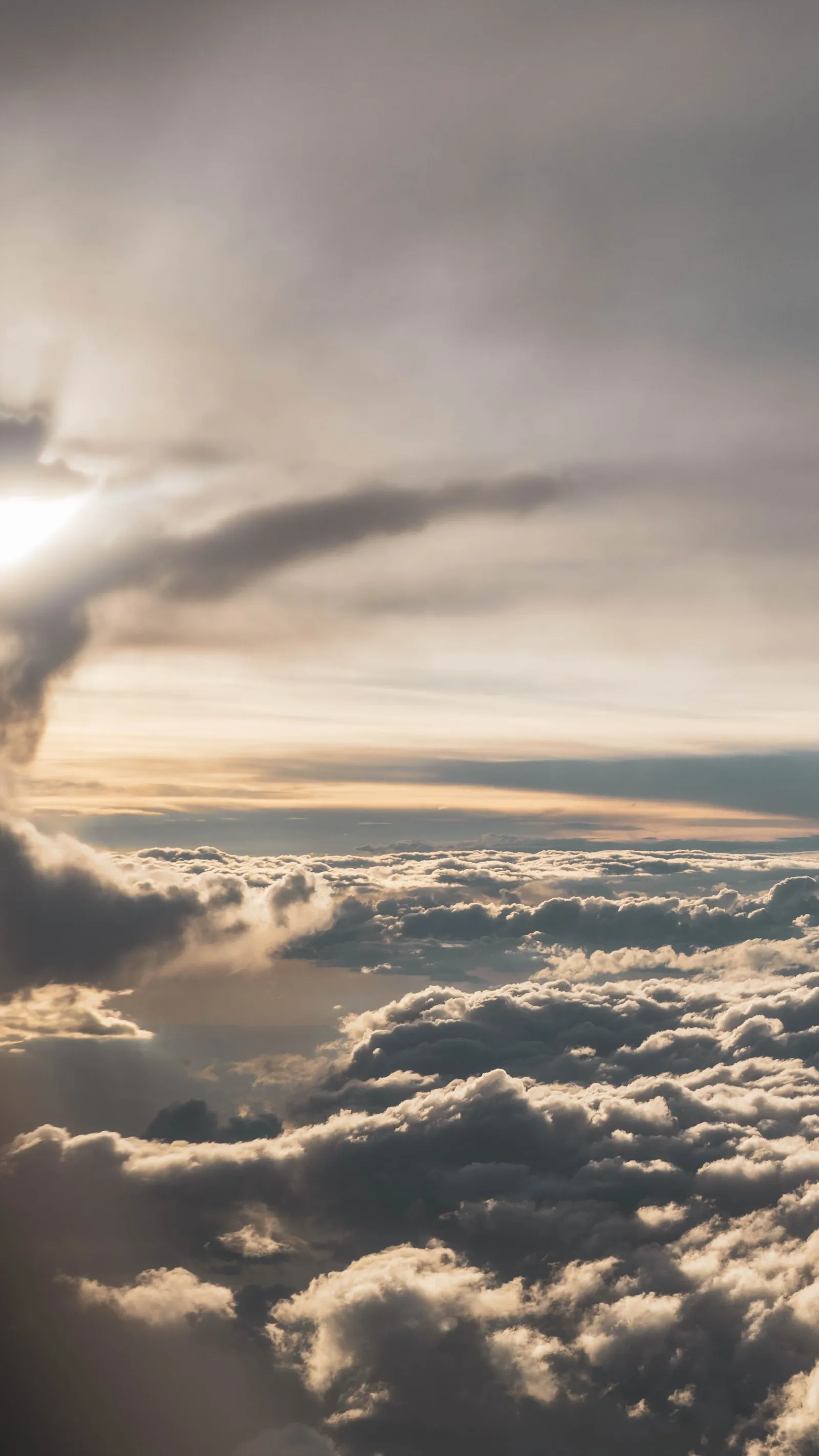 View from an airplane window of a sunlit cloud layer stretching to the horizon.