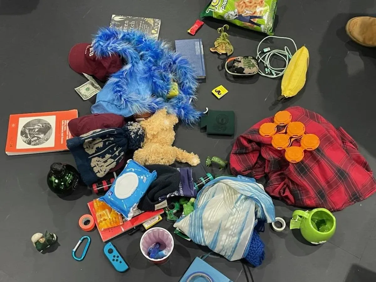 Closer overhead view of the same pile of collected personal items, including a teddy bear, plaid fabric, and a green mug.