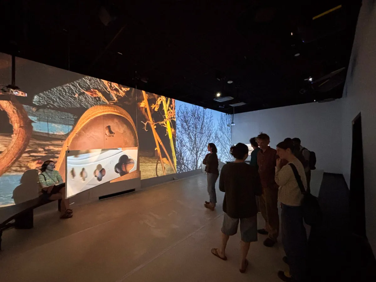 Wide installation view of the multi-screen Dream House exhibit, projected imagery of hands, texture, and bare winter trees wrapping around the gallery walls.